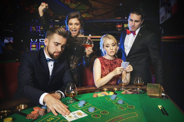 Losers and winners. Group of rich people is playing poker in the casino.
